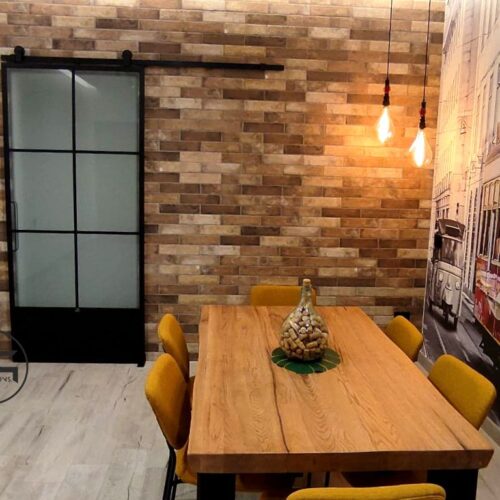un tavolo di legno con sedie gialle in una stanza con un muro di mattoni.